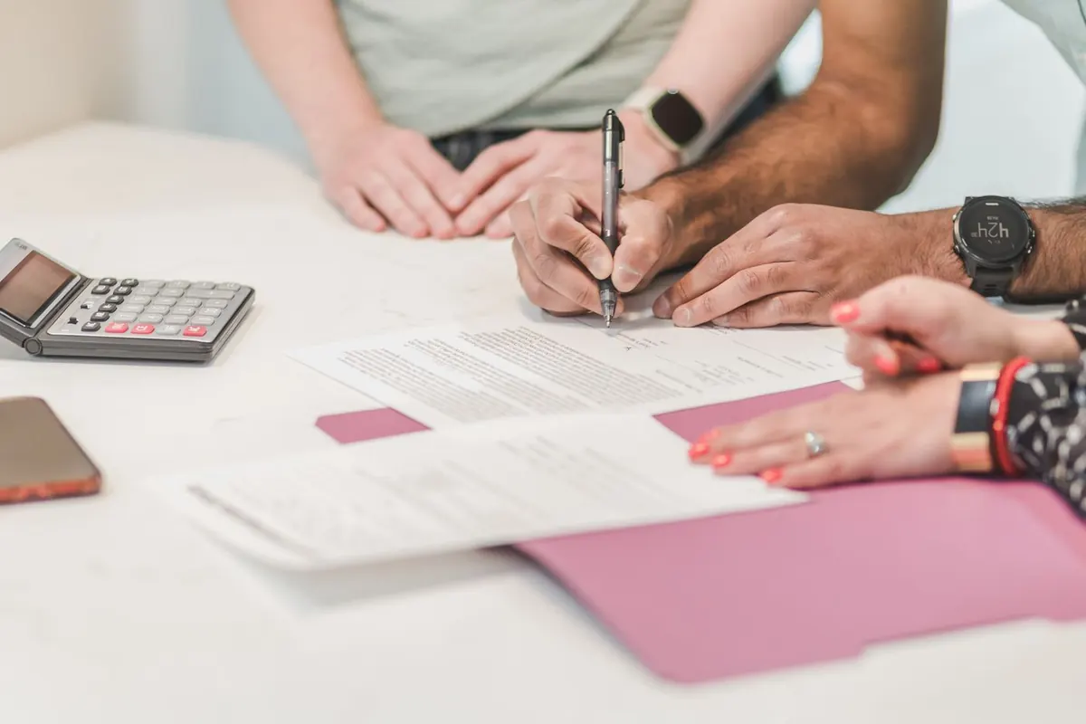 A person signing a loan agreement next to a calculator, comparing US personal loans by APR