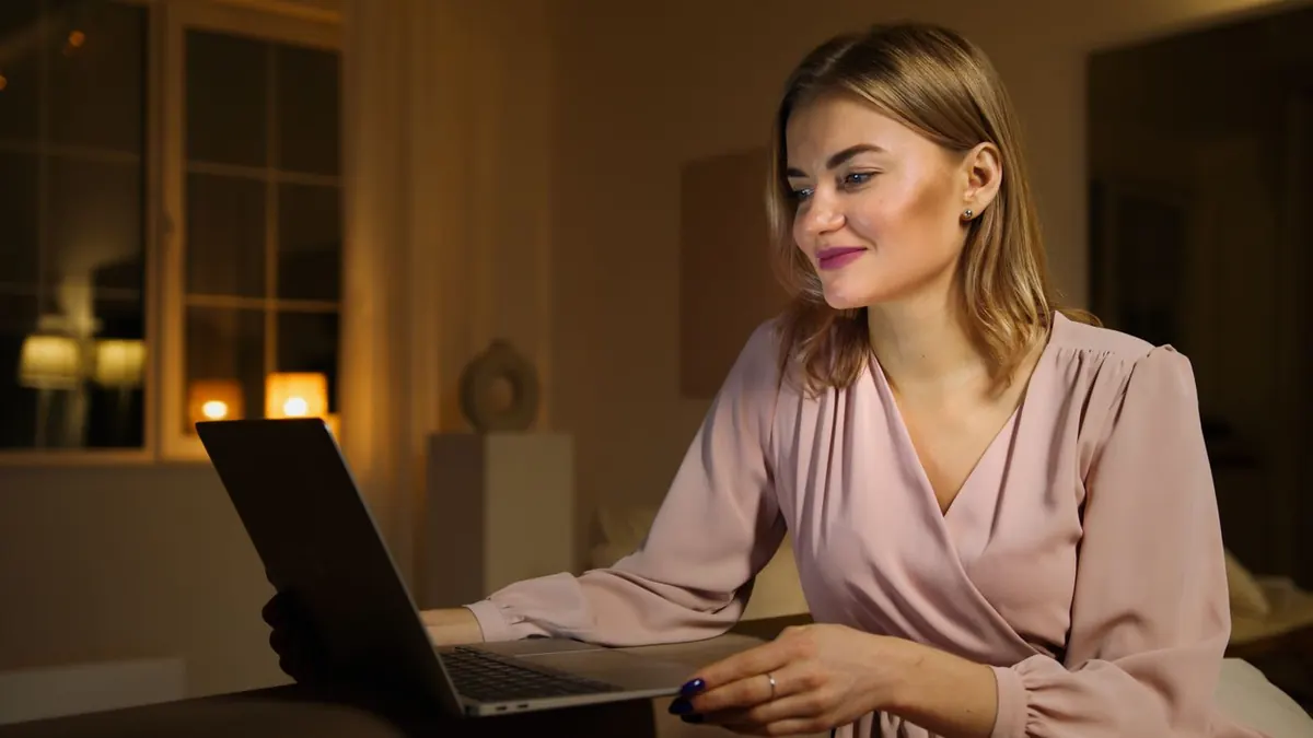 Une personne travaillant sur un ordinateur portable chez elle le soir, cherchant comment gagner plus d'argent