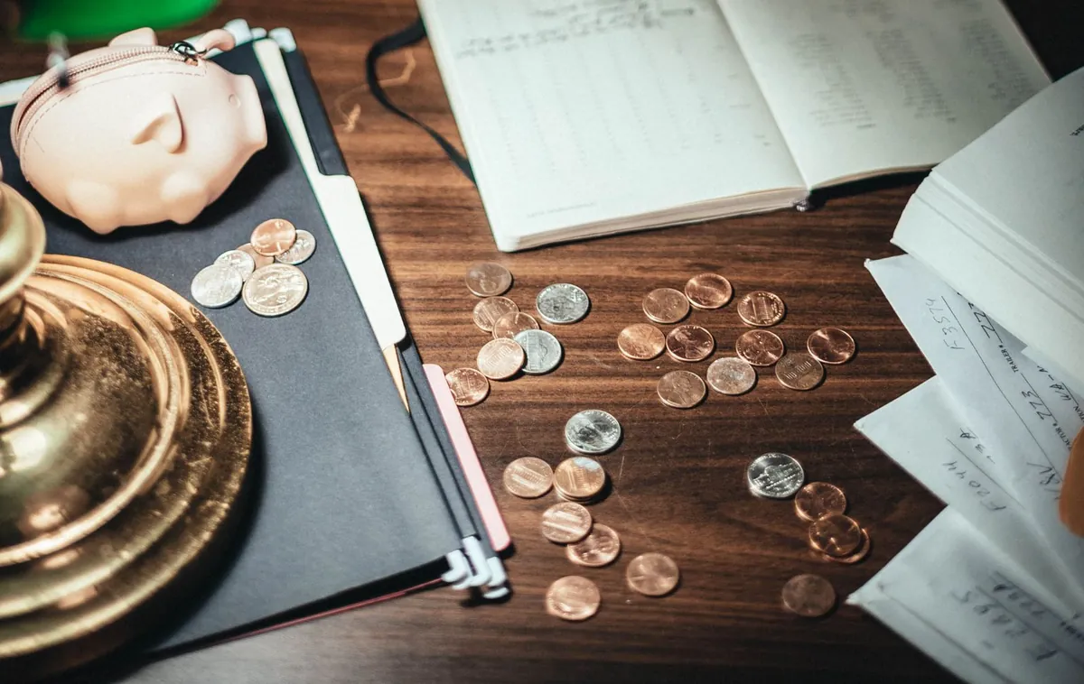 Coins, a piggy bank and financial planning papers on a desk illustrating how to build wealth from scratch