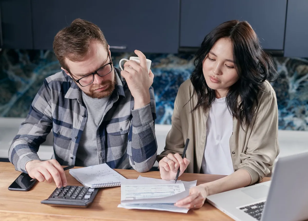Couple examinant ses factures et son budget sur un ordinateur portable et une calculatrice pour rembourser ses dettes vite