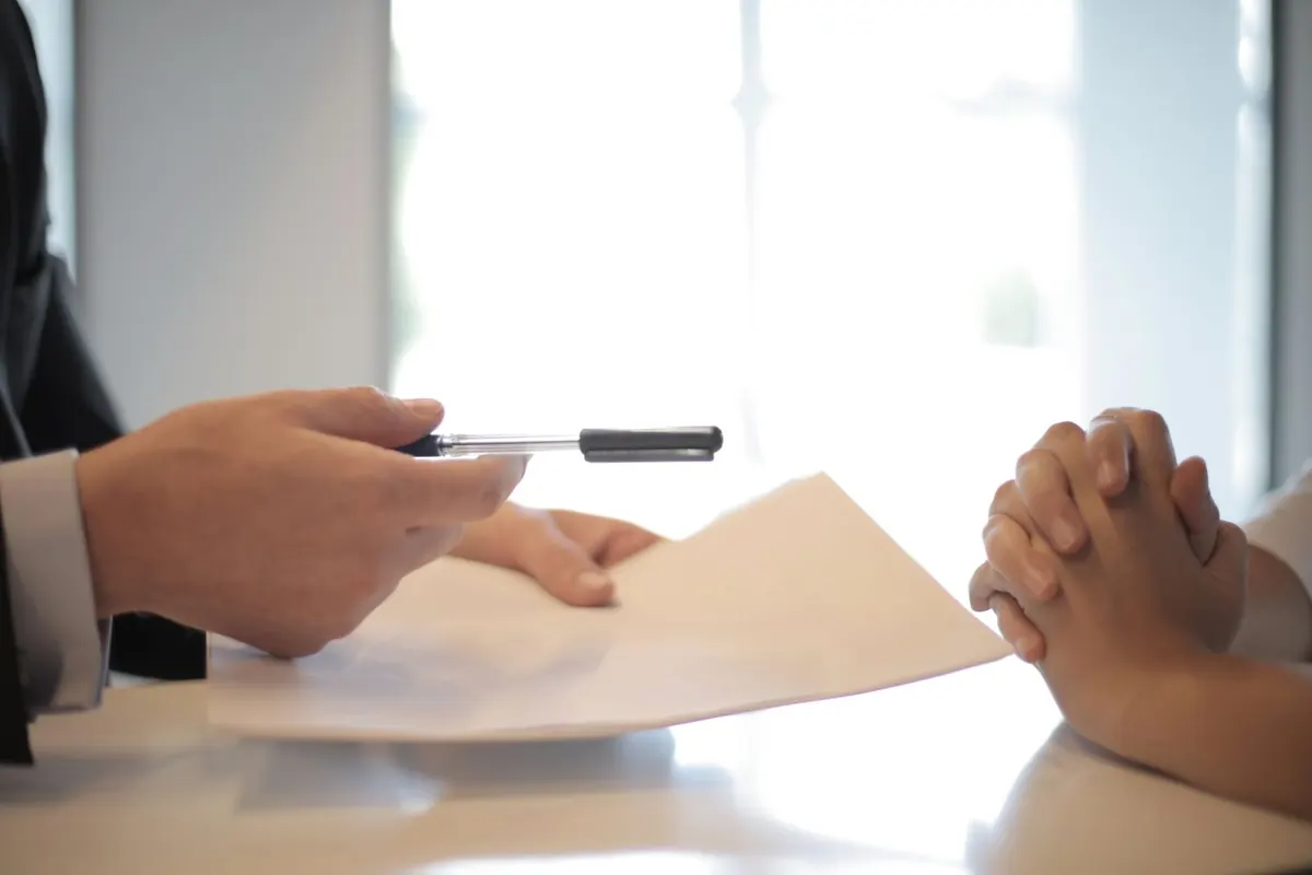 Une personne signant un contrat de prêt à côté d'une calculatrice, comparatif des prêts personnels en France
